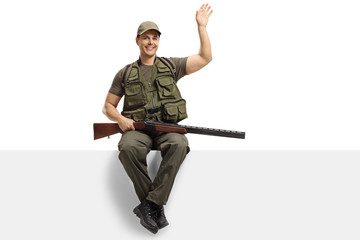 Hunter with a rifle sitting on a blank board and waving