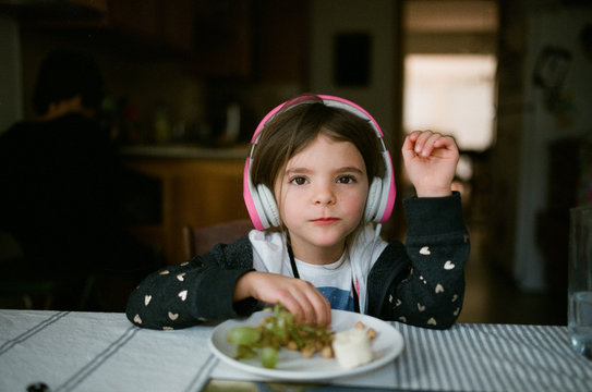 young girl eating grapes and wearing headphones