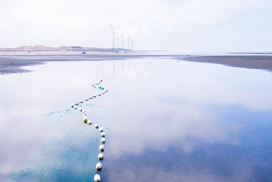 Sea reflected blue sky, and fishing net buoys float on the sea.