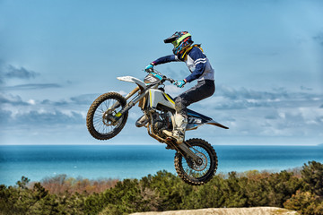 Naklejka na ściany i meble Extreme sports, motorcycle jumping. Motorcyclist makes an extreme jump against the sky. Film grain effect, illumination