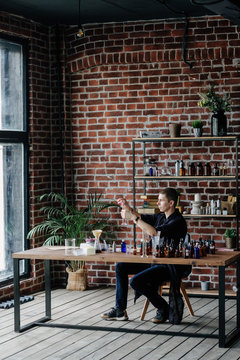 Young man at table in perfume workshop