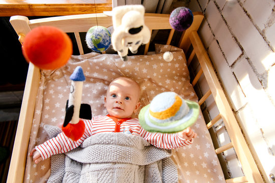 Funny baby in infant bed with mobile