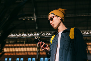 Chinese young man using a cellphone in the train station