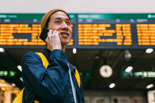 Young asian man talking on cellphone in airport terminal