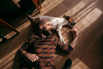 the guy is lying on the floor with the dog and laughing