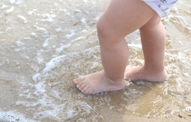 small children's feet walk on the wet sand of the sea