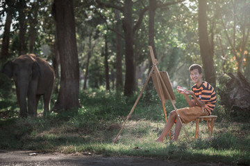 Asian boy with Down's syndrome is happily drawing a picture of an elephant in the garden.Drawing,...