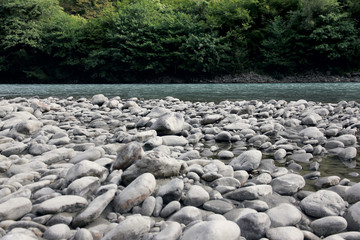 Bank of a mountain stony river in Abkhazia, strewn with large stones