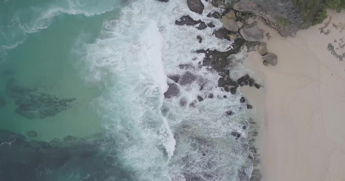 Aerial view of the waves crashing towards the beautiful white sand beach, raw footage, ungraded, no color, log profile