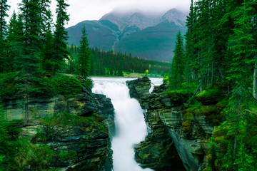 Fototapeta na wymiar Spectacular Waterfall In Beautiful Rocky Mountain Forest.
