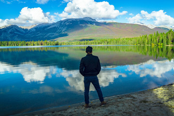 Fototapeta na wymiar Young Man At Calm Reflection On Outdoor Scenic Lake In Evening