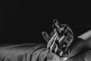 Close up on female young woman's girl's beautiful hands woman lying on the bed black and white nail...