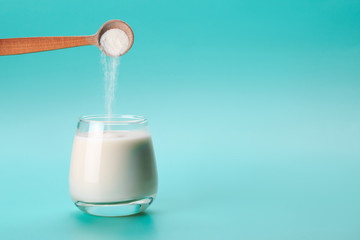 Coconut or almond milk with collagen sponon blue background with palm leaf