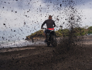  Man ride on the motorbike at the ocean black sand beach