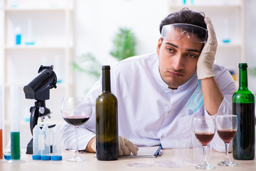 Male chemist examining wine samples at lab