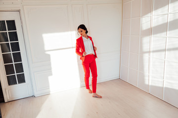 Portrait of a beautiful fashionable brunette woman in a red business suit in a business office