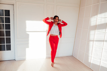 Portrait of a beautiful fashionable brunette woman in a red business suit in a business office