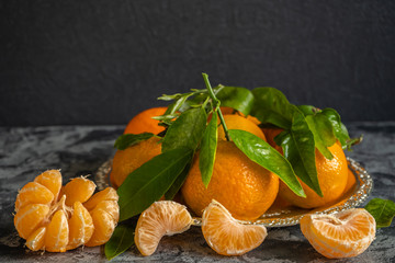 Fresh mandarins with branch and green leaves on a metal plate