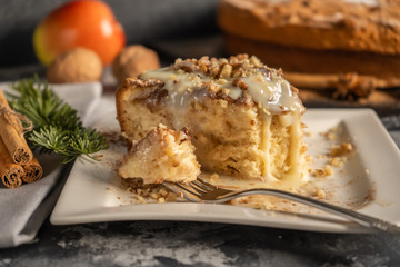 Apple pie with cinnamon on the table, a piece of apple pie with condensed milk and walnuts on a white plate