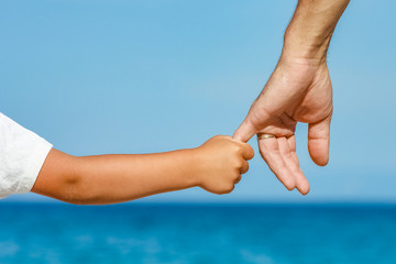 happy dad holds the hand of a child by the greek sea in nature