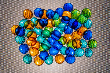 Multicolored oval and round pieces of glass are illuminated through a textured background