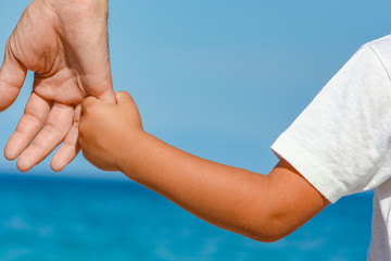 happy dad holds the hand of a child by the greek sea in nature