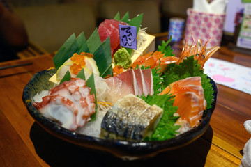 The beautifully decorated sashimi mixed on a black bowl is a popular Japanese dish.