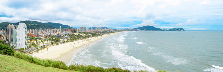Panoramic aerial view of the Cove Beach at Guaruja SP Brazil. People on the beach, the sand, sea waves and the city on background. Place known as Praia da Enseada. Brazilian coastal city.