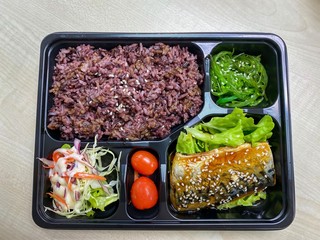 Saba fish grilled with teriyaki sauce on topped rice bowl in the plastic container