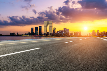 Fototapeta premium Asphalt road and Suzhou city skyline with beautiful colorful clouds at sunset.