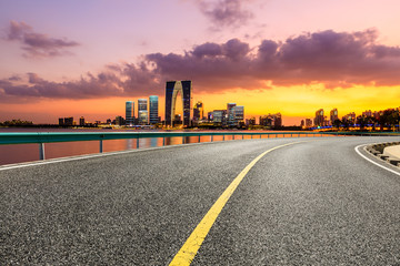 Asphalt road and Suzhou city skyline with beautiful colorful clouds at sunset.