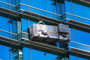 Professional high rise window cleaning service workers use specialized equipment to access and clean the windows of tall building