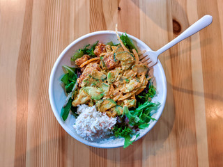 Spicy tuna and salmon poke bowl with white rice, sitting on a wooden table
