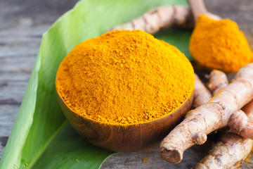 Turmeric powder in wooden bowls on old wooden table. Herbs