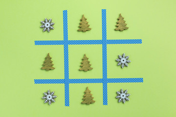 Tic tac toe game with christmas toys, isolated on green background. Christmas, winter concept. Flat lay, top view.