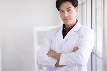 Asian scientists wear white robes standing by the window in the laboratory. And smiling at the camera