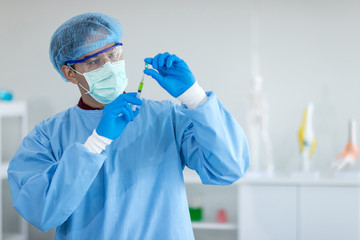 Asian scientists wear protective clothing while using a syringe to test viral drugs in the laboratory.