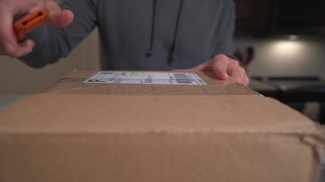 Close up of man cutting open a recent online shopping purchase