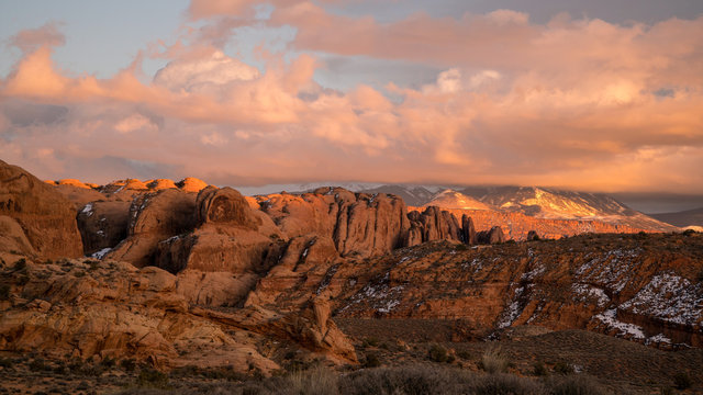 Colorful sunset over desert rocky fin layers in Moab looking towards the La Sal Mountains with colorful clouds.