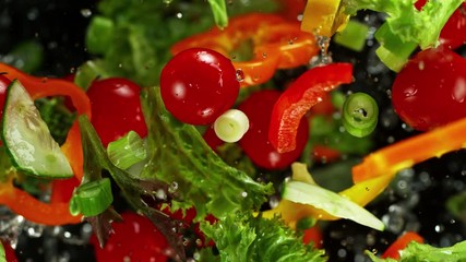 Super Slow Motion Shot of Flying Cuts of Colorful Vegetables and Water Drops on Black background at 1000fps.