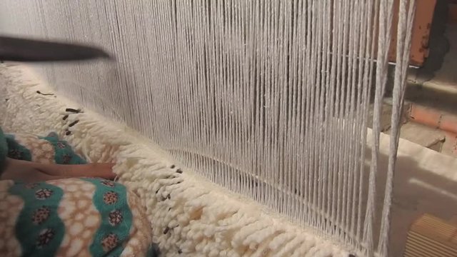 close up on a Moroccan girl weaving a carpet with a manual waving machine, Carpet weaving , Needlework , Morocco .