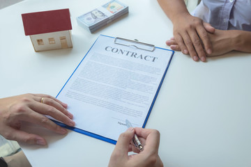 Contacting the buying or selling of real estate through a sales representative offering a contract to buy a house or apartment, condo and providing house keys for success.