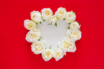 White roses put as heart shape on red background with white space for text for Valentine’s day. Flat lay background concept.