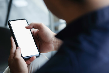 Cropped shot view of man hands holding smart phone with blank copy space screen for your text message or information content, female reading text message on cell telephone during in urban setting. 