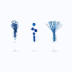 Set of blue New Year decoration in champagne glass isolated on white background. Minimal flat lay and color of Year 2020 concept. Christmas ball, beans and tinsel composition. Winter holiday.