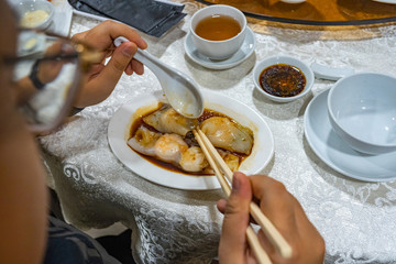 Human using chopsticks while eating Chinese steamed shrimp rolls