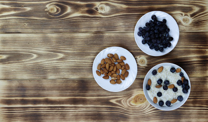 Oatmeal porridge with blueberries and almonds on wooden background