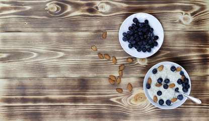 Oatmeal porridge with blueberries and almonds on wooden background