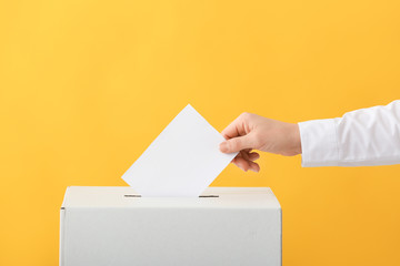 Voting woman near ballot box on color background - obrazy, fototapety, plakaty