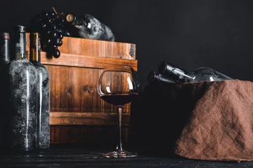 Schilderijen op glas Bottles and glass of wine on table in cellar © Pixel-Shot
